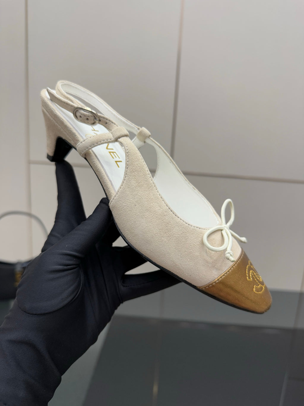 Women’s slingback heel held up, white upper with gold toe cap and lace tie
