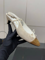 Women’s slingback heel held up, white upper with gold toe cap and lace tie