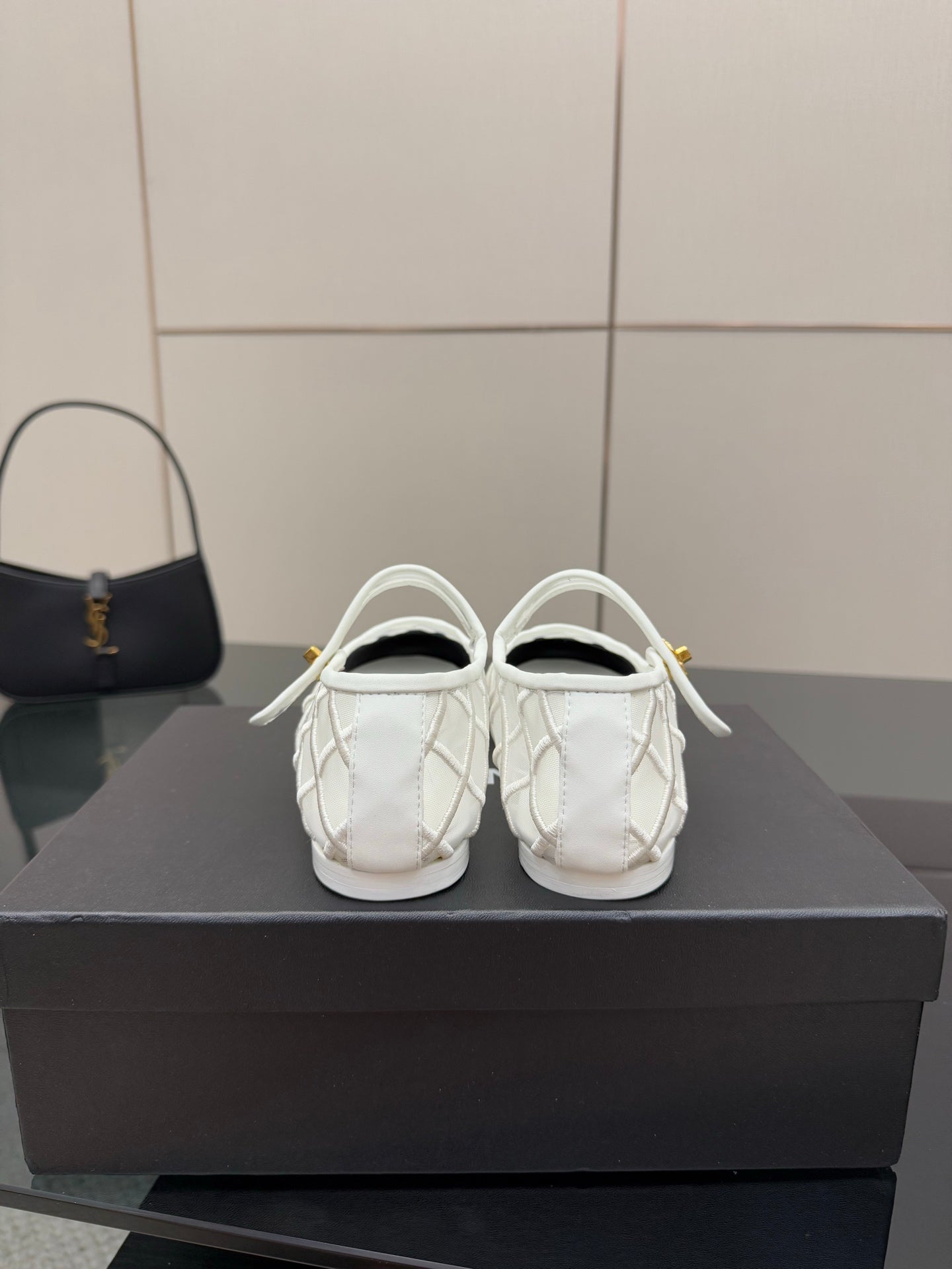 White lattice sneakers with black toe, gold emblem at top strap