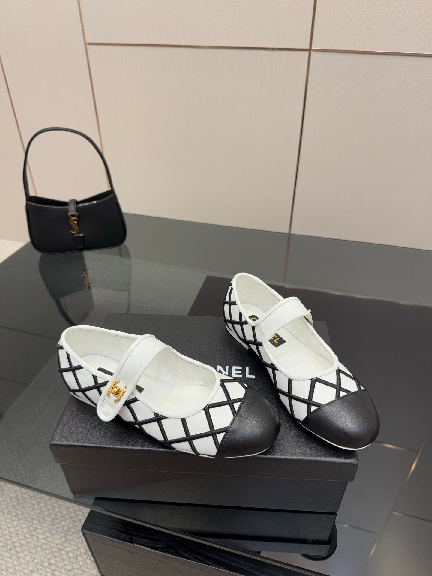 Pair of women's slip-on flats, white uppers with black crisscross pattern and gold detail