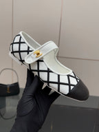 Close-up of women's slip-on flats, black lattice over white with gold logo on strap