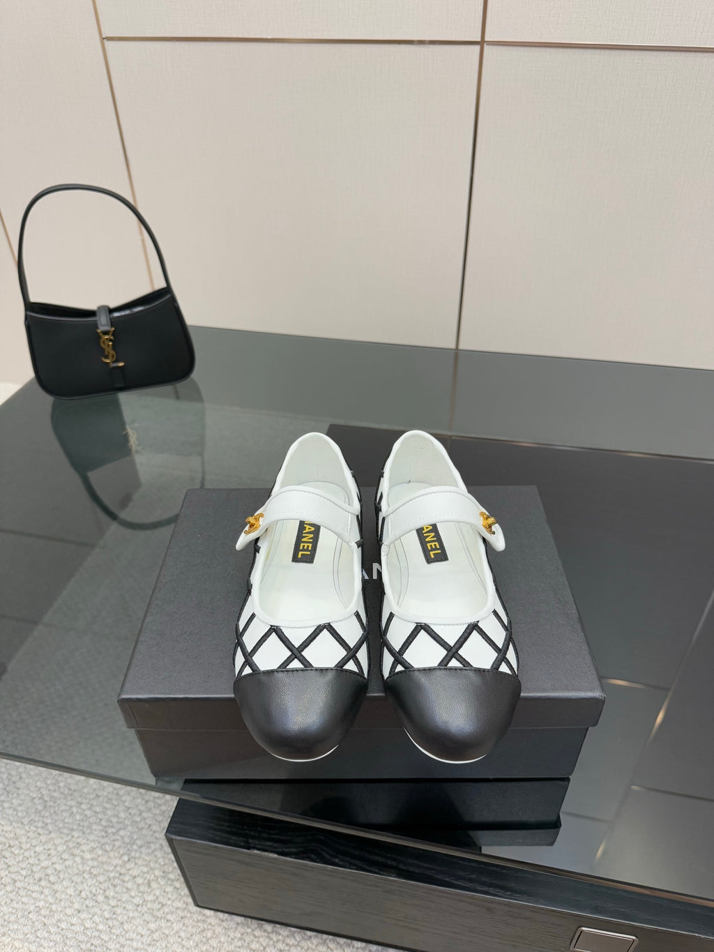 Women's slip-on flats with black lattice panels and white uppers, gold logo detail