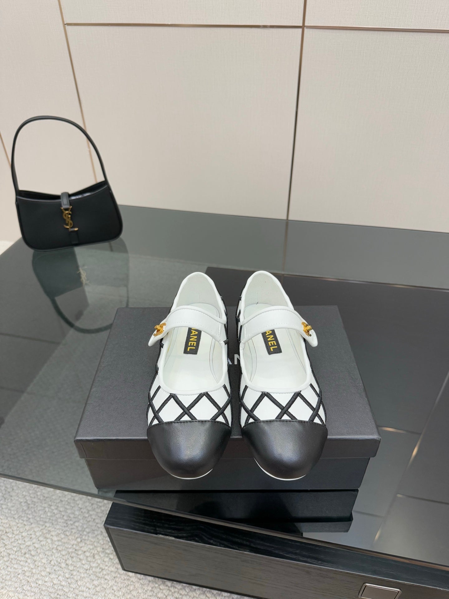 Women's slip-on flats with black lattice panels and white uppers, gold logo detail