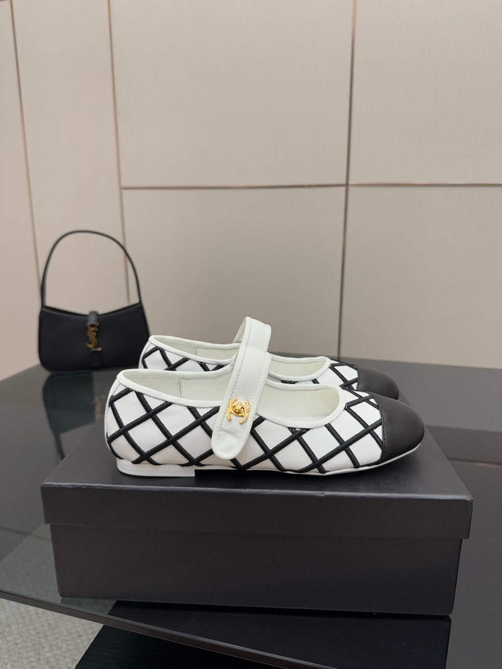 Women's slip-on flats on display: white upper with black grid pattern and gold emblem