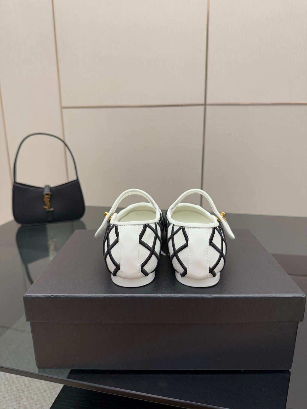 Back view of women's slip-on flats, white and black lattice design with gold accents