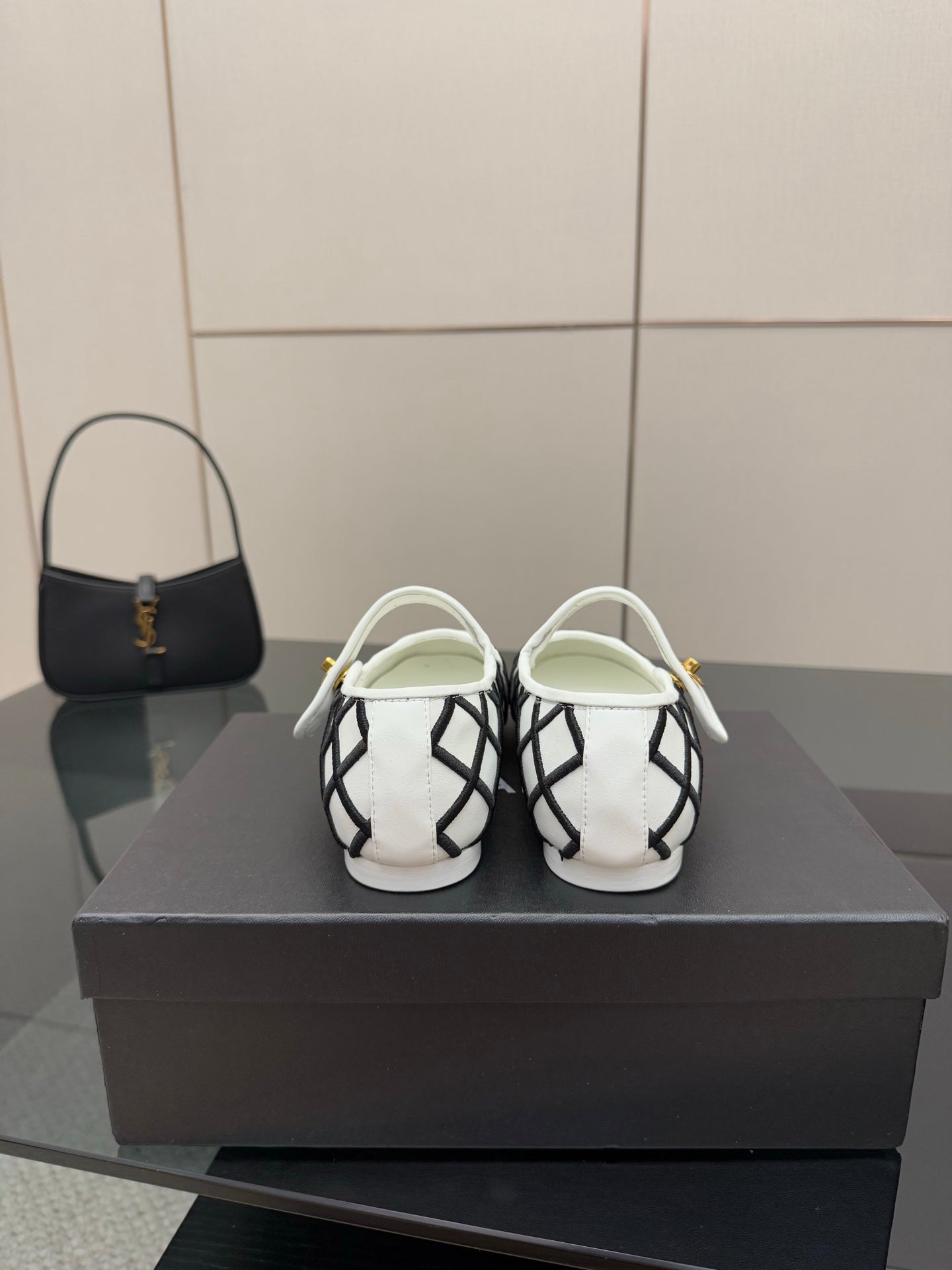 Back view of women's slip-on flats, white and black lattice design with gold accents