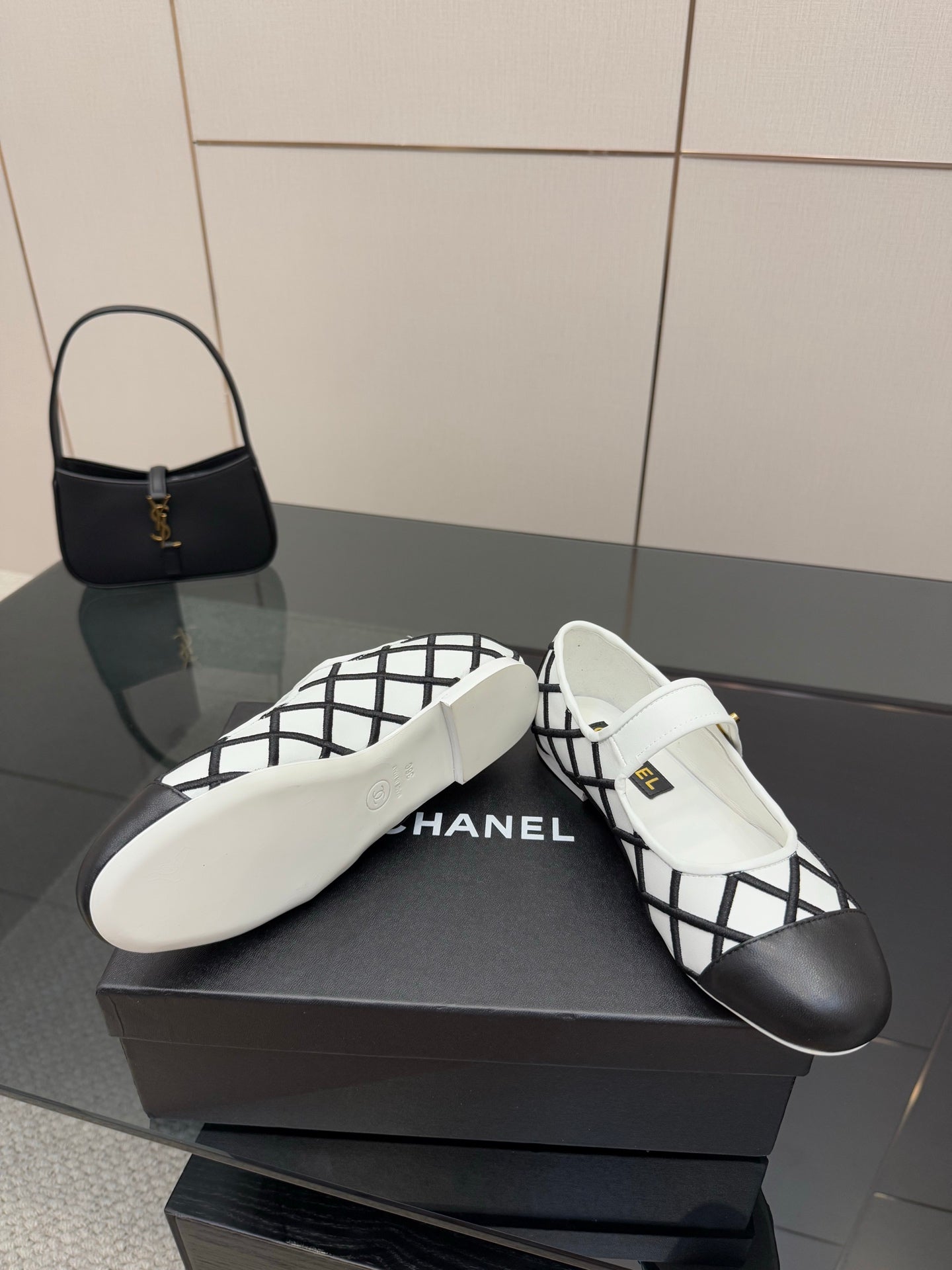 Women's slip-on flats, white leather with black lattice trim, featuring CHANEL logo