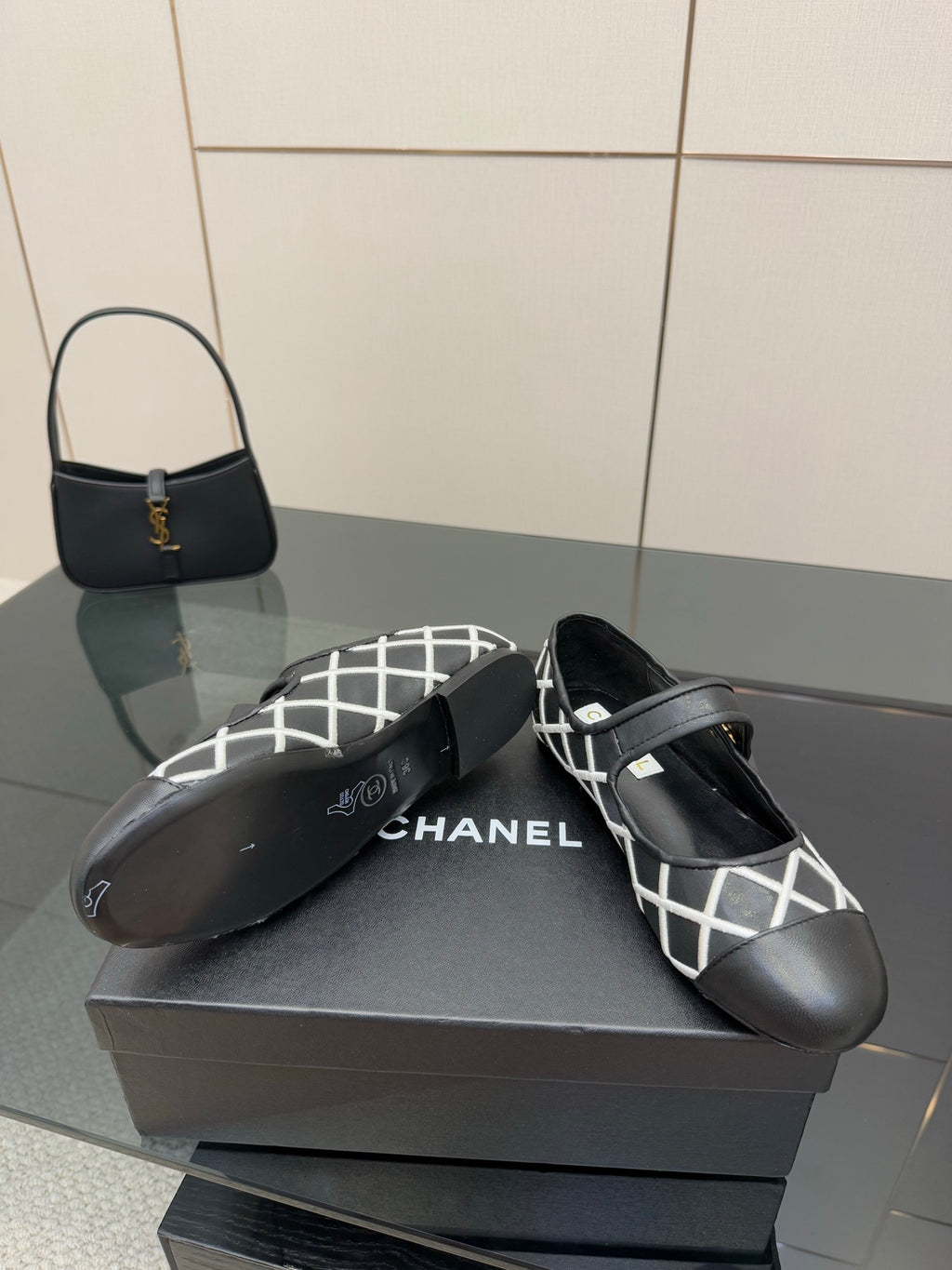 Black Chanel flats with white lattice upper and gold logo accent on strap