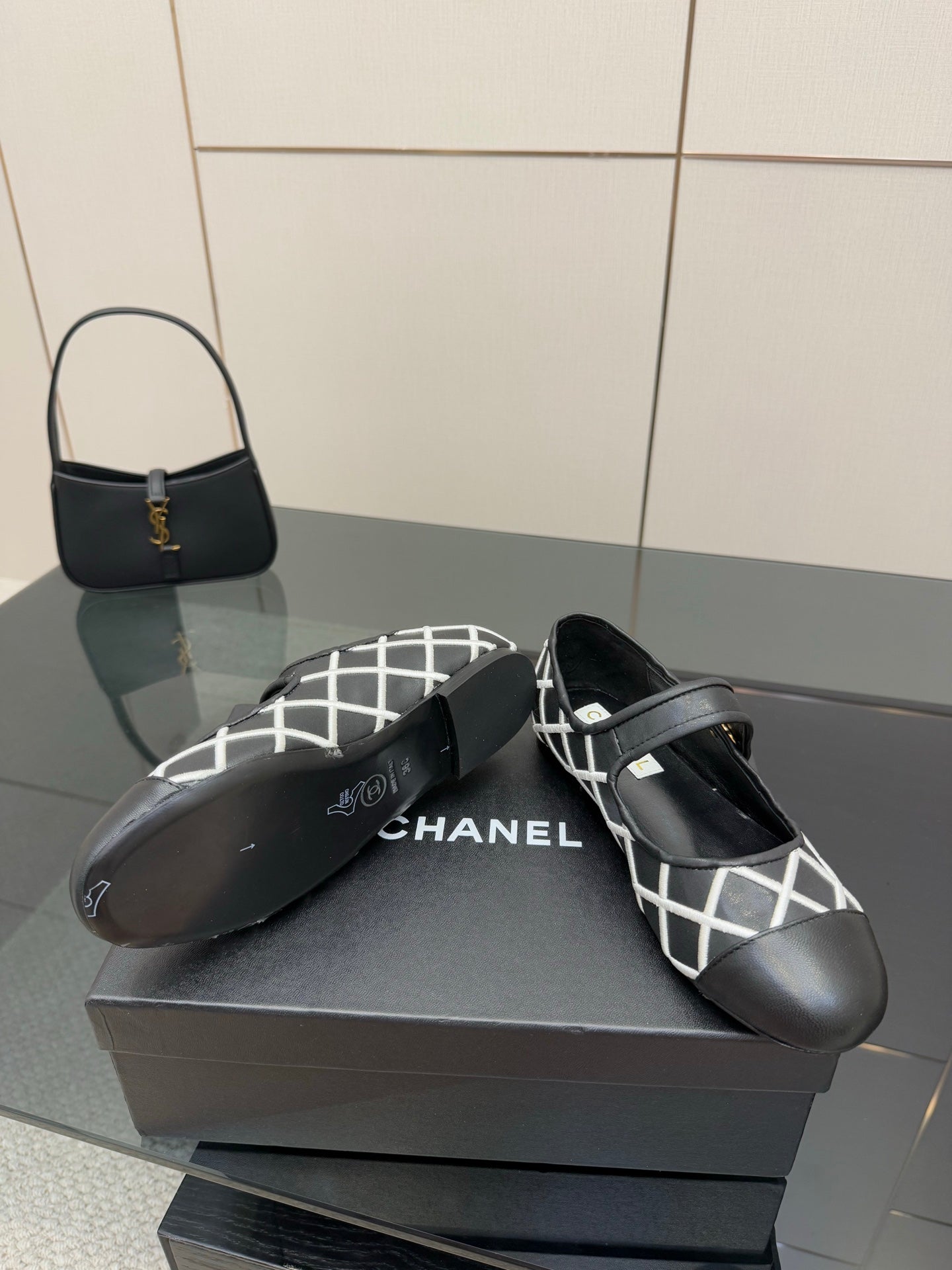 Black Chanel flats with white lattice upper and gold logo accent on strap