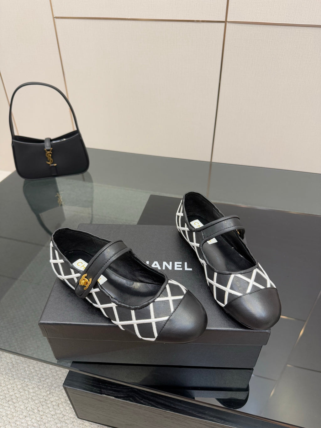 Pair of black Chanel flats with white lattice strap and gold logo buckles