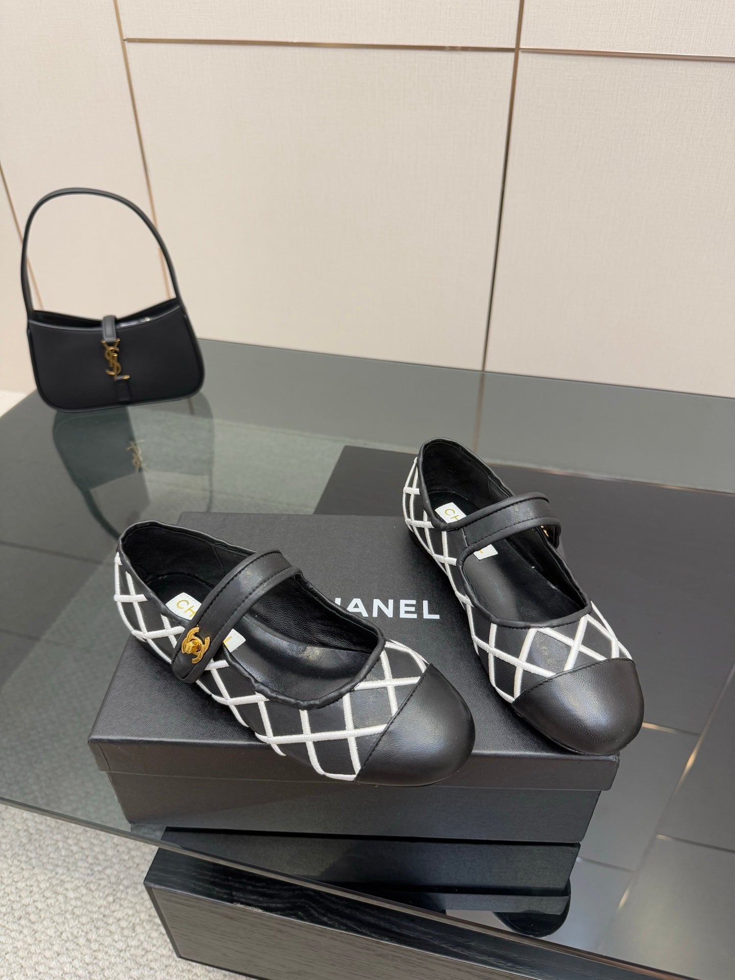 Pair of black Chanel flats with white lattice strap and gold logo buckles