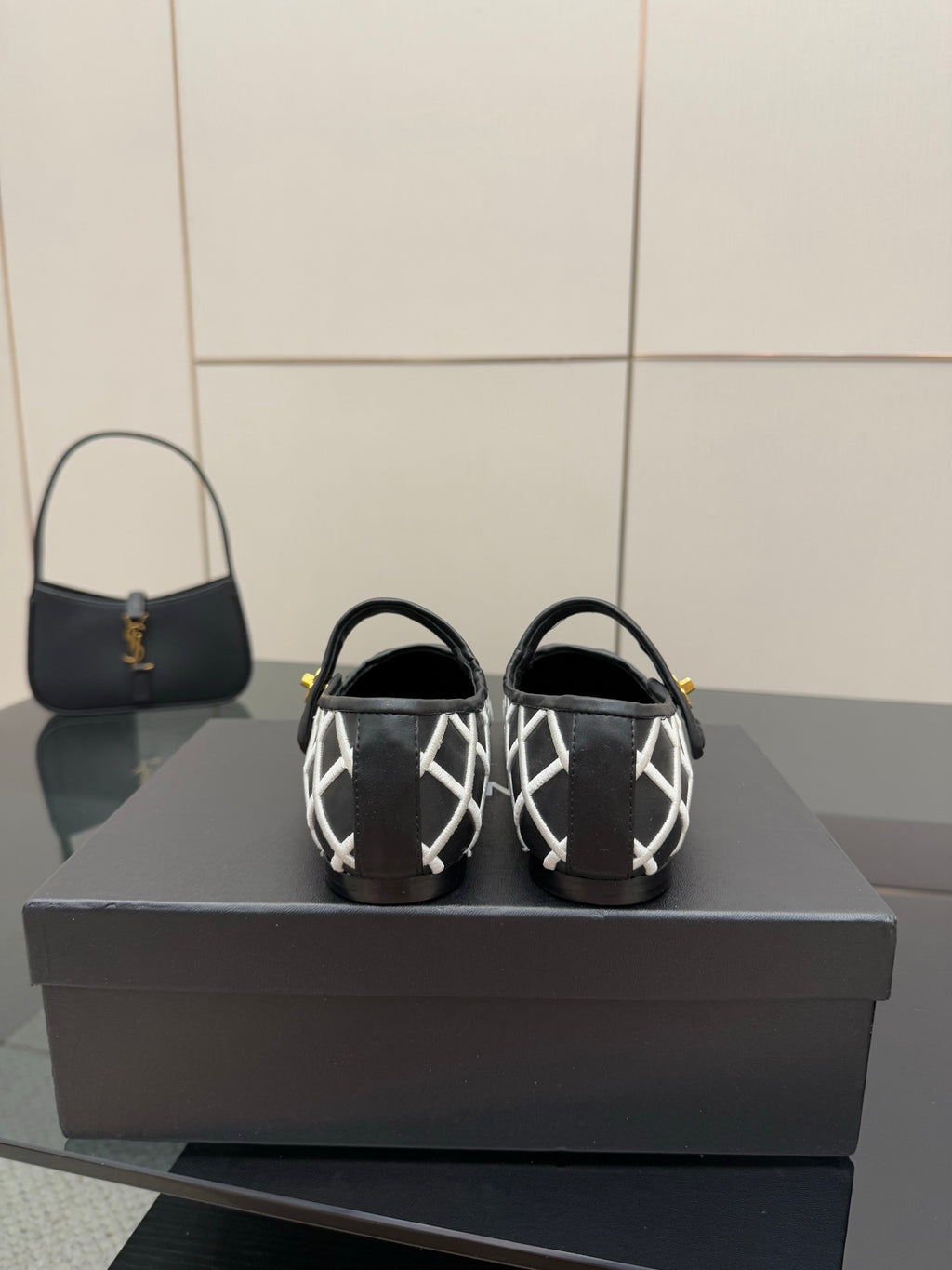 Black Chanel flats showing heel straps with white lattice pattern and gold logo