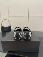 Black Chanel flats showing heel straps with white lattice pattern and gold logo