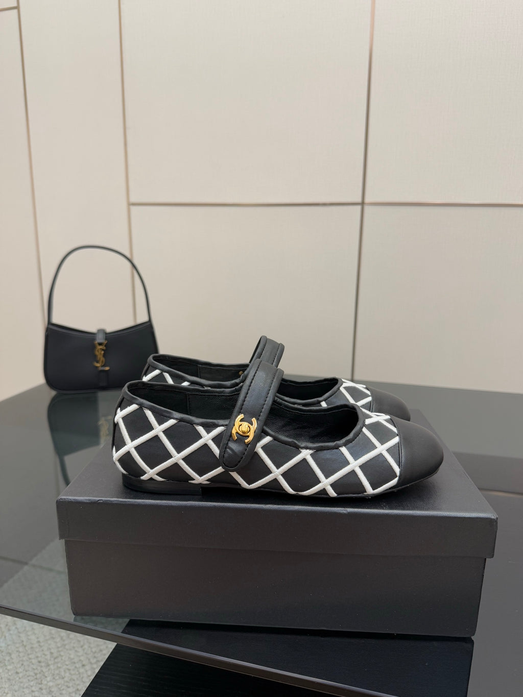 Black Chanel flats with white grid strap and gold logo center detail