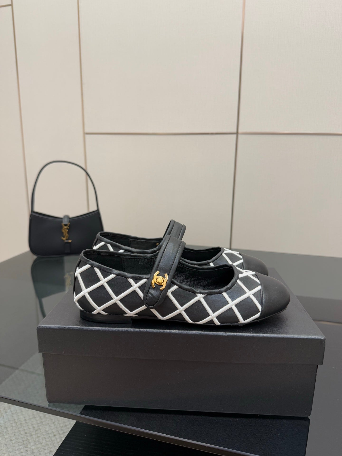 Black Chanel flats with white grid strap and gold logo center detail
