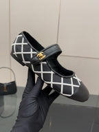 Black Chanel flats held by hand, white lattice trim and gold logo on strap