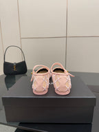 Pink sandals with white crisscross straps and gold buckle detail