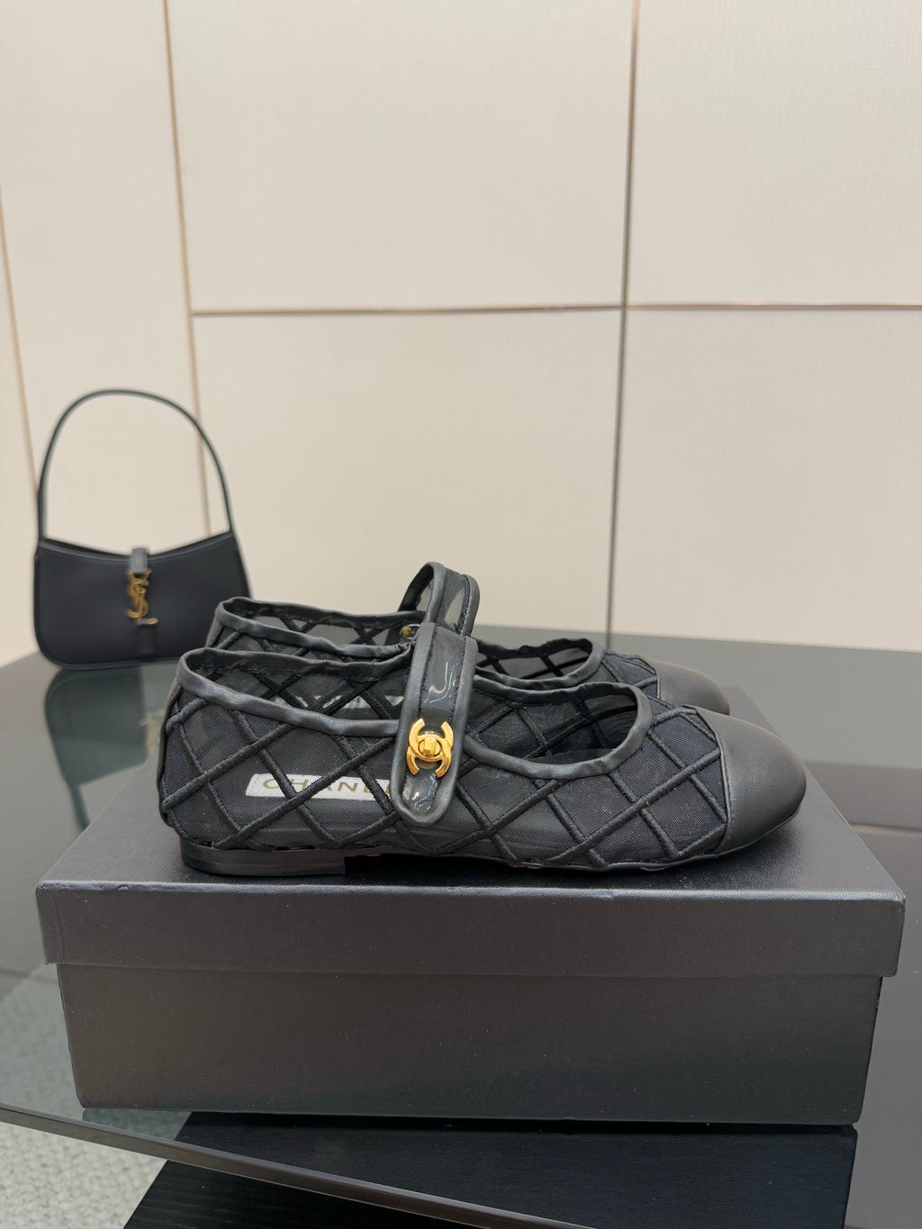 Chanel women’s black quilted flat with gold CC charm, side view on box
