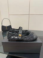 Chanel women’s black quilted flat with gold CC charm, side view on box