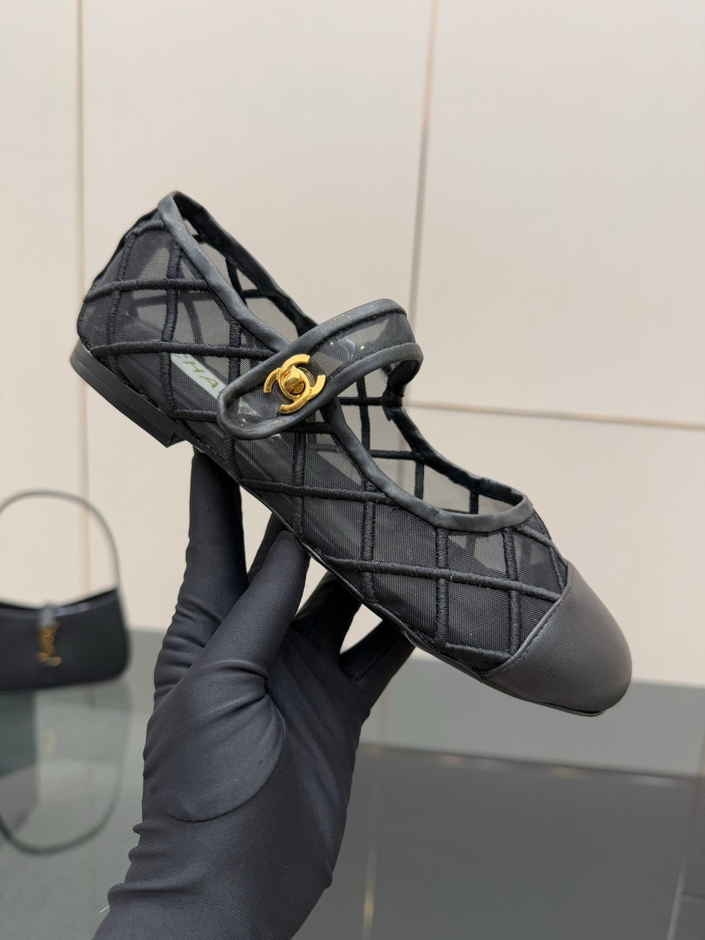 Chanel women’s black quilted flats held in hand, gold CC on front strap