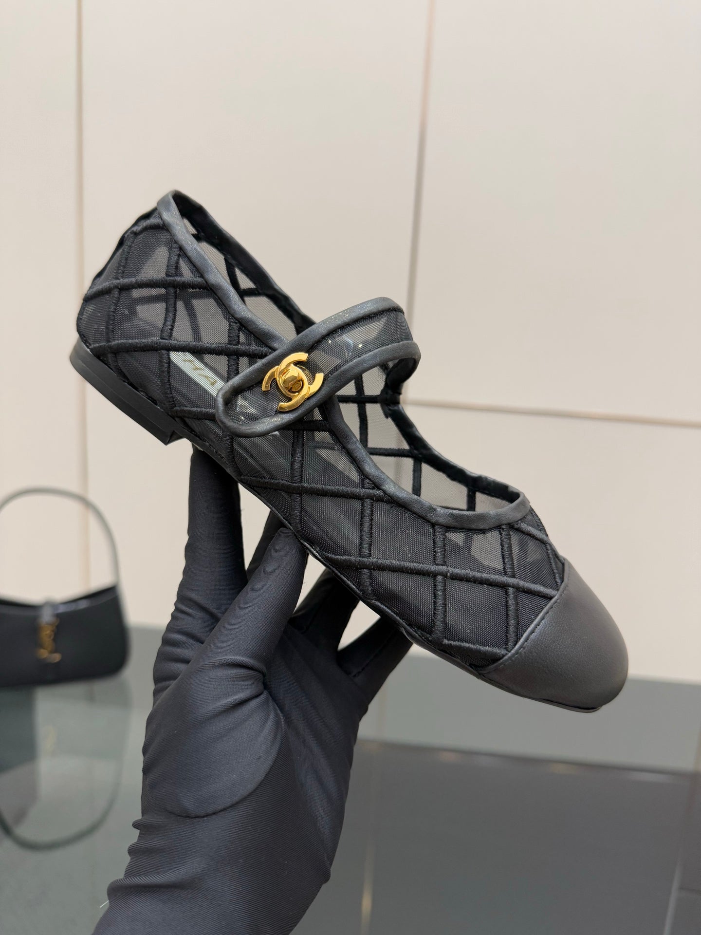 Chanel women’s black quilted flats held in hand, gold CC on front strap