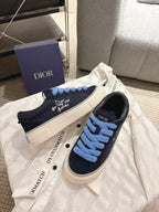 Navy low-top sneakers with light blue laces and white sole, DIOR logo near heel