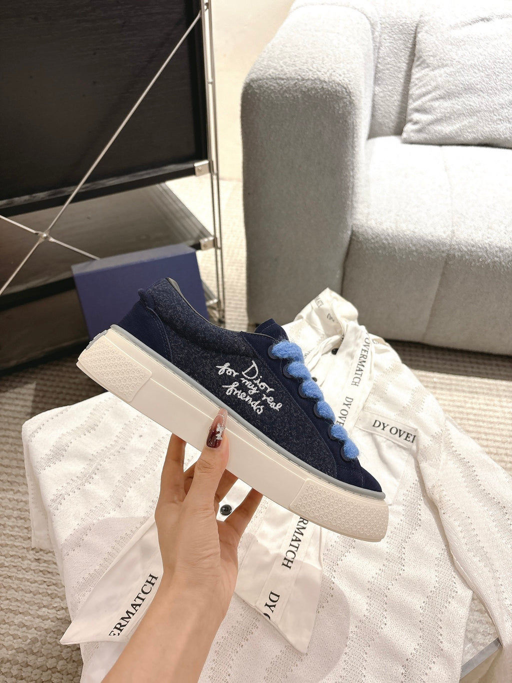 Navy low-top sneakers with light blue laces and white sole, DIOR branding on upper