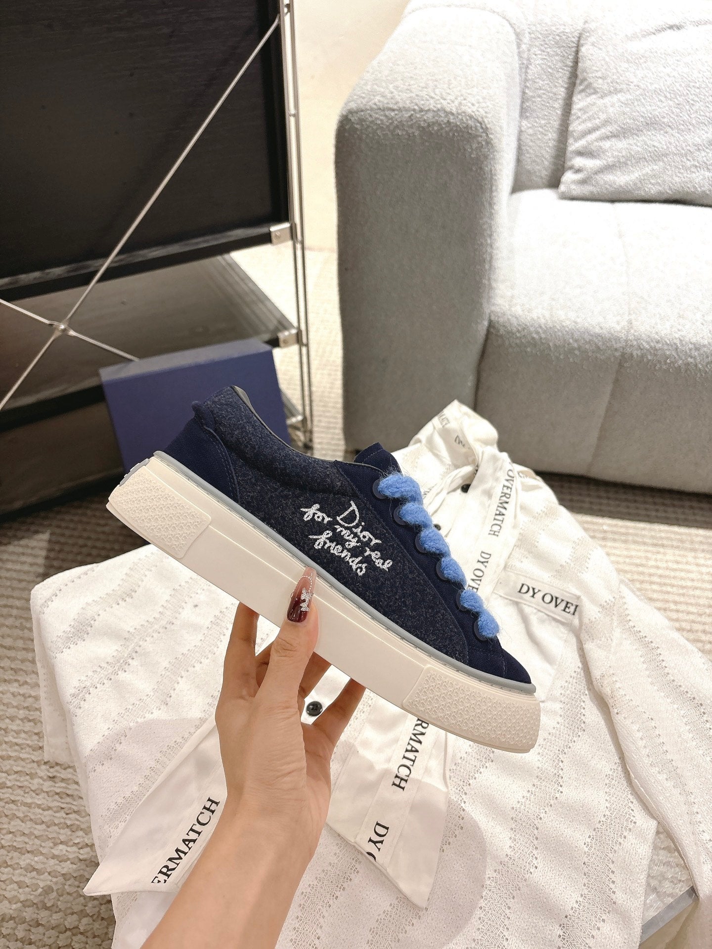 Navy low-top sneakers with light blue laces and white sole, DIOR branding on upper