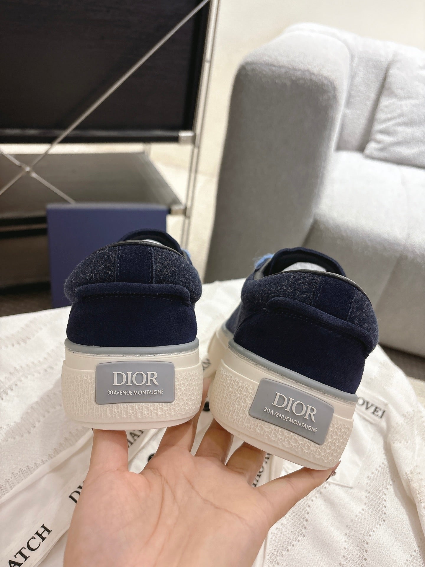 Back view of navy low-top sneakers with white heel panel and DIOR label