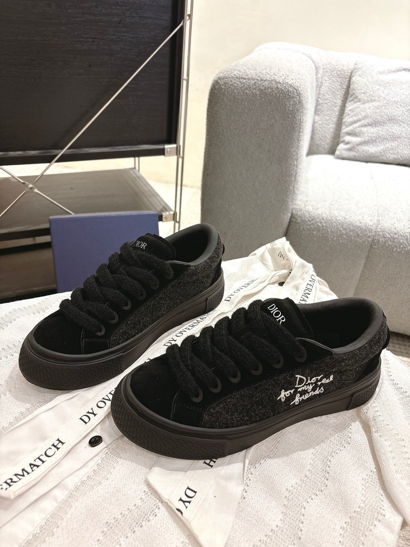Pair of black lace-up Dior sneakers on display, front quarter view and cushioned tongue