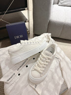 White Dior sneakers angled side view, lace-up closure with chunky rubber sole