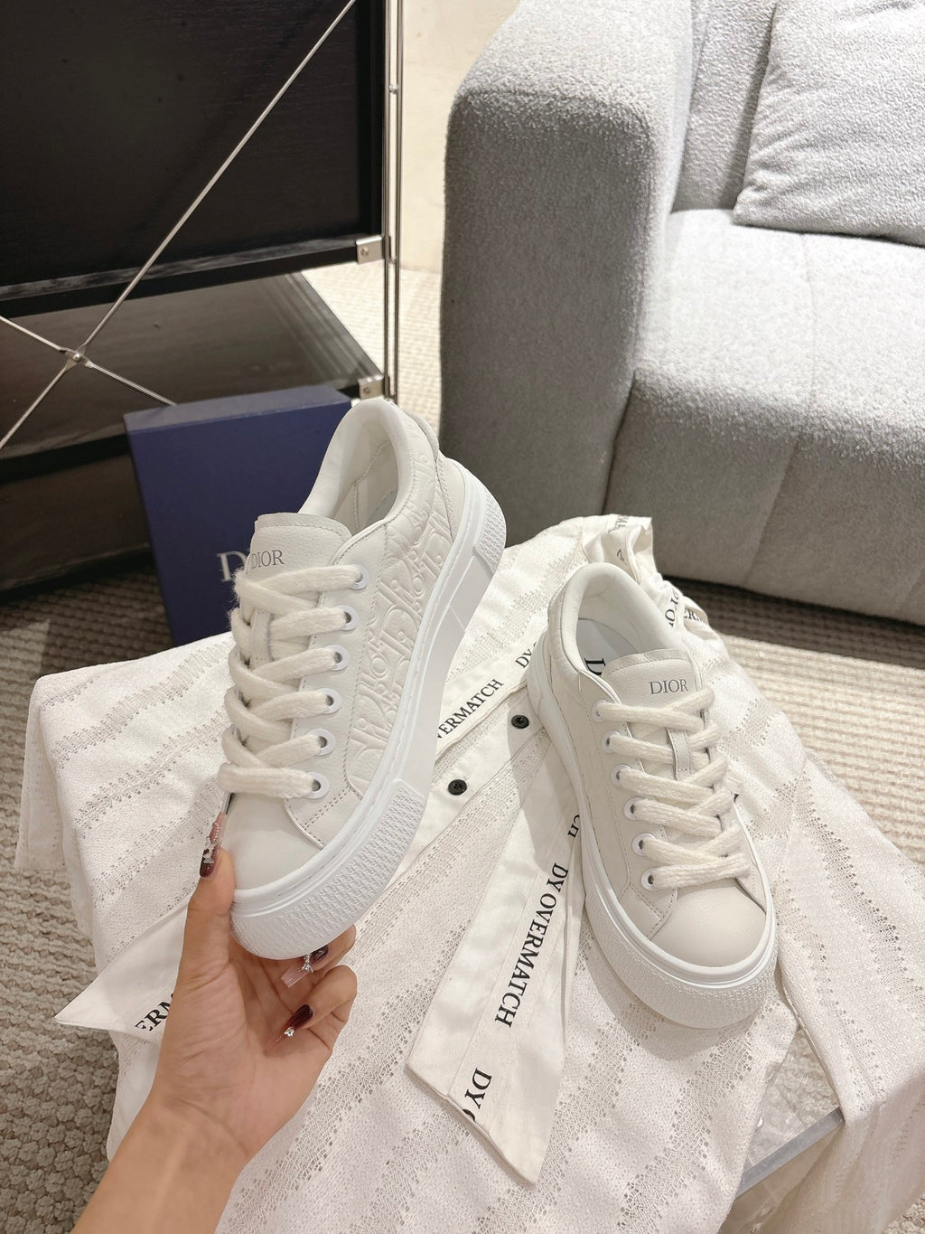 White Dior sneakers side view, lace-up with logo printed on the tongue