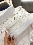 White Dior sneakers top view, lace-up eyelets and textured leather-like upper
