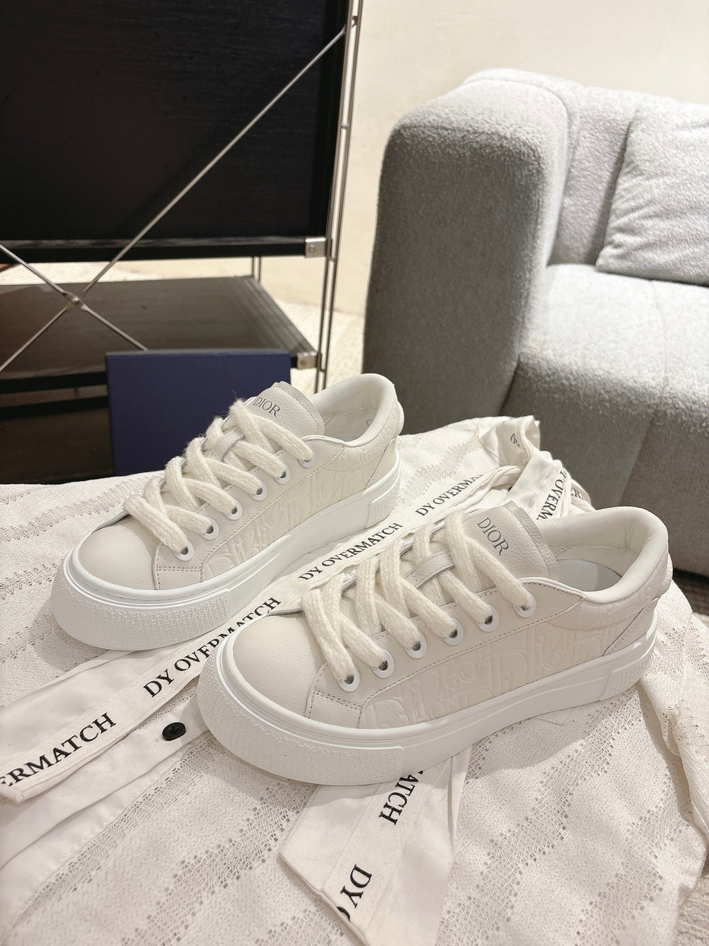 White Dior sneakers, side view with ridged rubber sole and lace-up upper