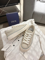 Light beige low-top sneakers on dust bag, lace-up with side logo detail