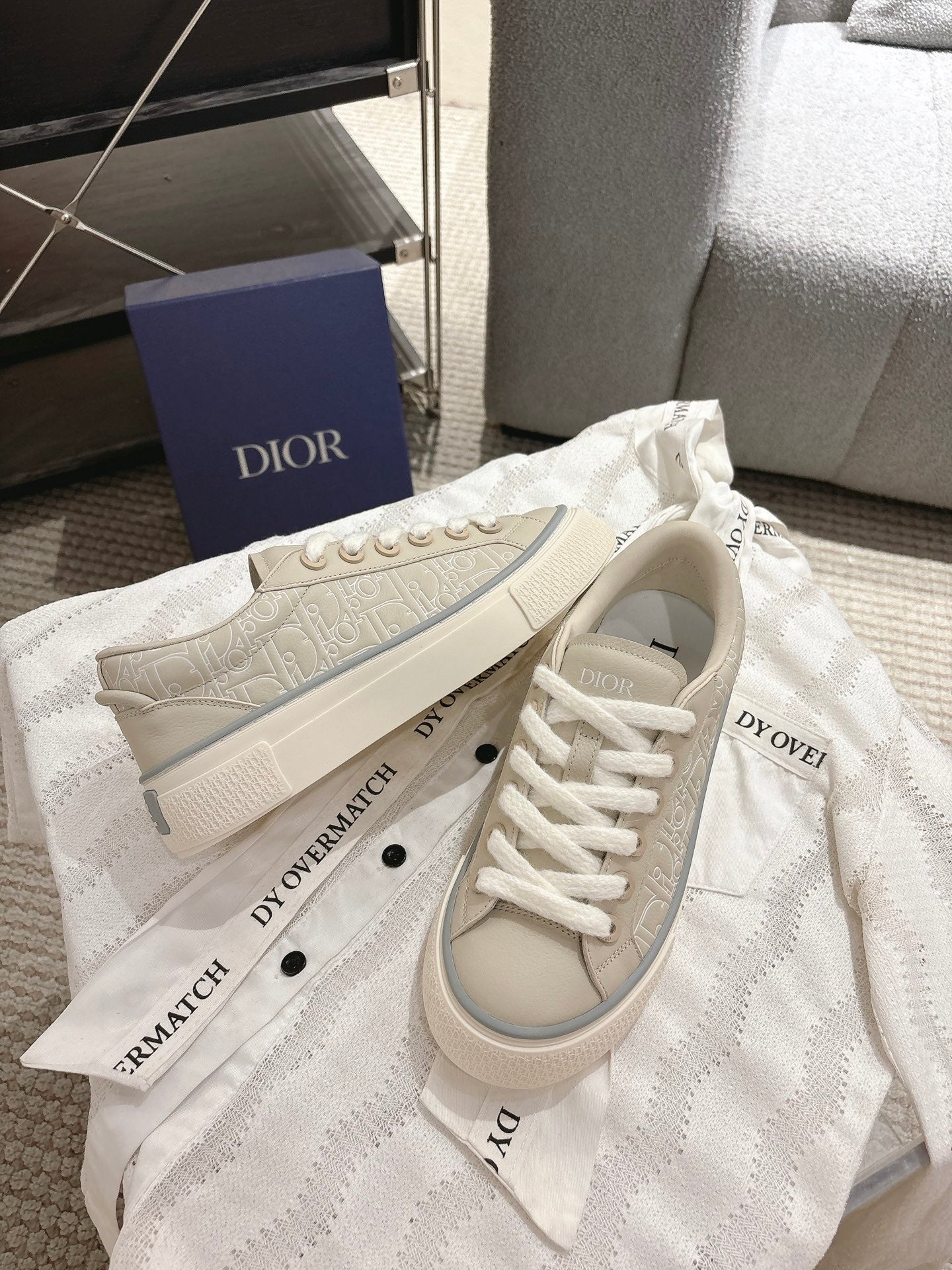 Light beige low-top sneakers on dust bag, lace-up with side logo detail