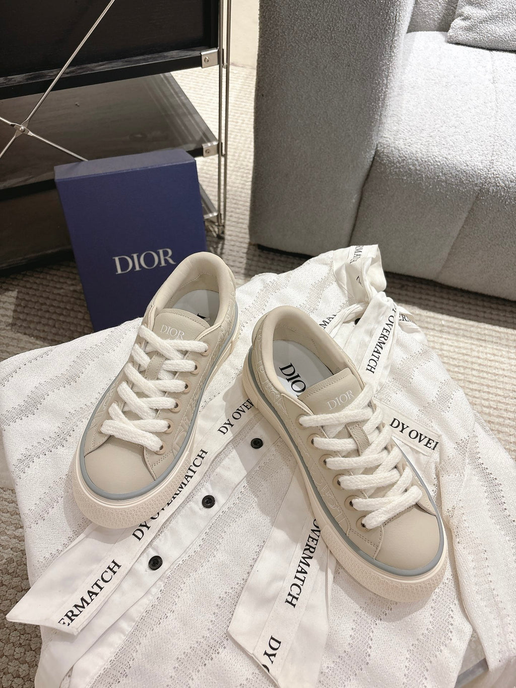 Light beige low-top sneakers with printed tongue labels and white lace-up