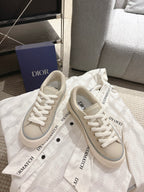 Light beige low-top sneakers with printed tongue labels and white lace-up