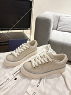 Light beige low-top sneakers with textured upper and white laces, side view