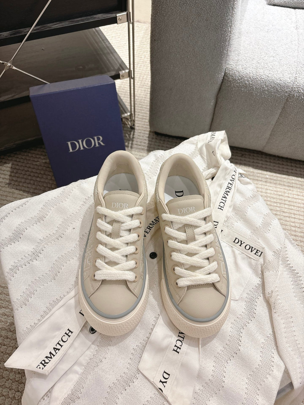 Light beige low-top sneakers with white laces and embroidered brand accents