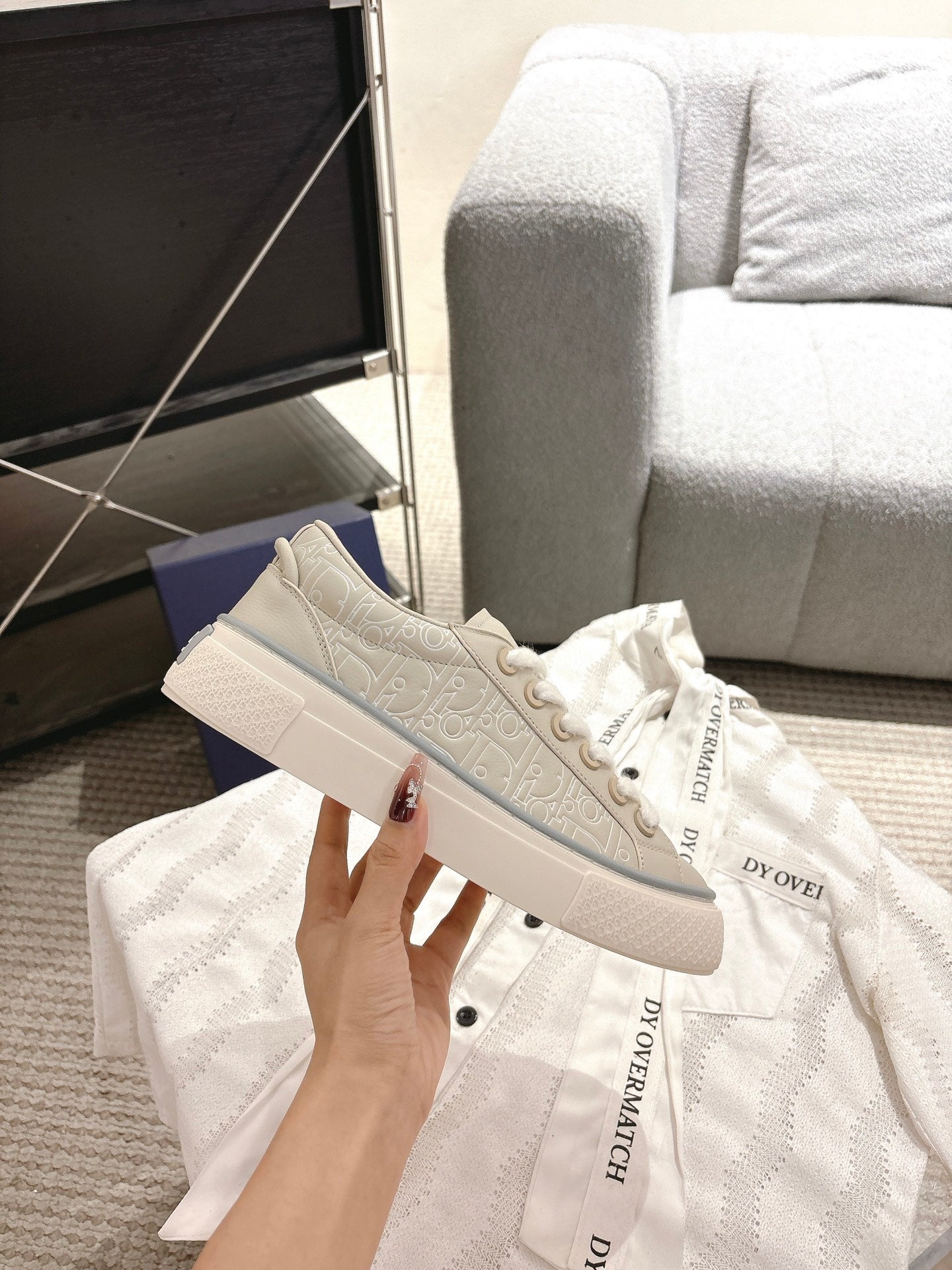 Light beige low-top sneakers with subtle monogram print on side and white laces