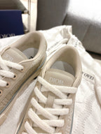Light beige sneakers close-up with white laces and monogram-pattern panels
