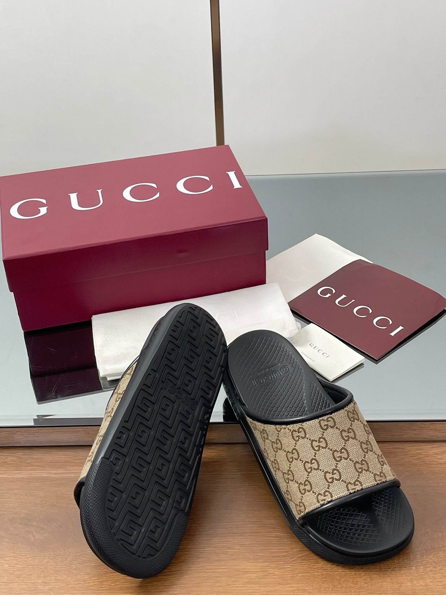 Gucci slide sandals with beige GG canvas uppers and black outsole tread