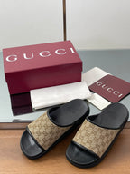 Gucci slide sandals with beige GG canvas straps over black cushioned footbeds