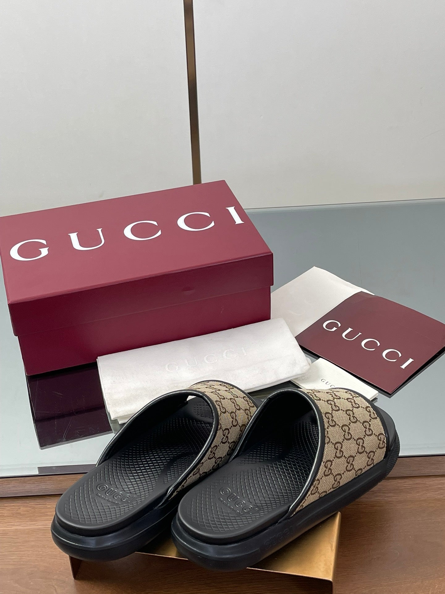 Gucci slide sandals with beige GG canvas straps and black rubber slide soles