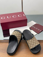 Gucci slide sandals with beige GG canvas straps and black rubber footbeds