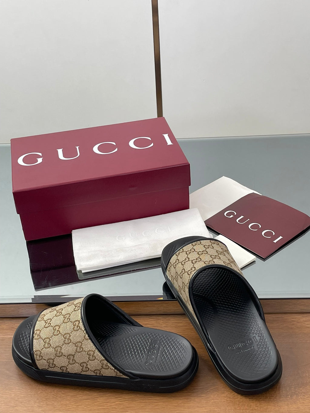 Gucci slide sandals with beige GG canvas straps and black contoured footbeds