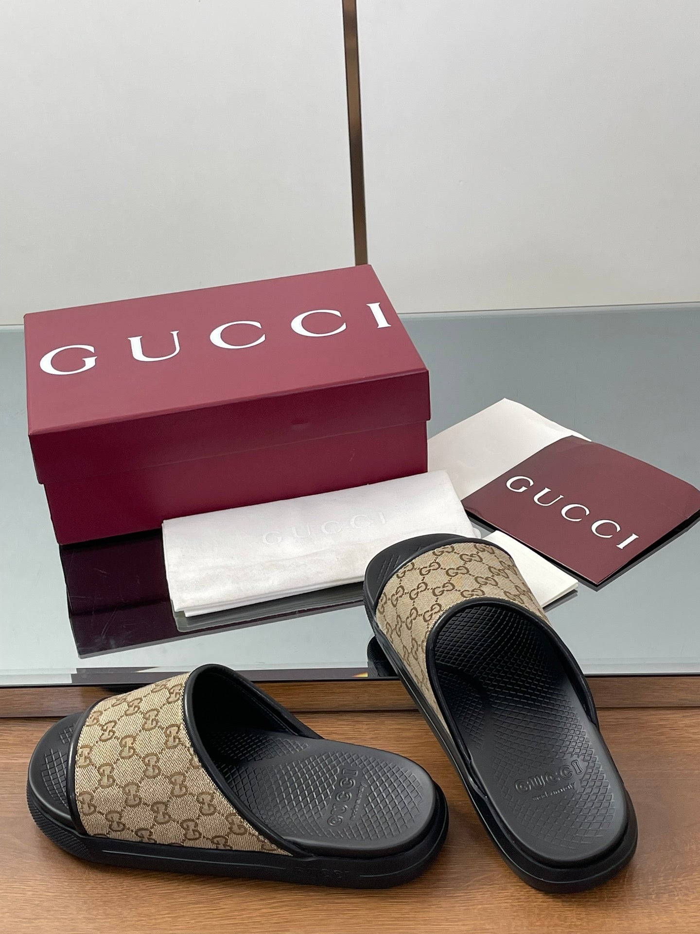 Gucci slide sandals with beige GG canvas straps and black contoured footbeds