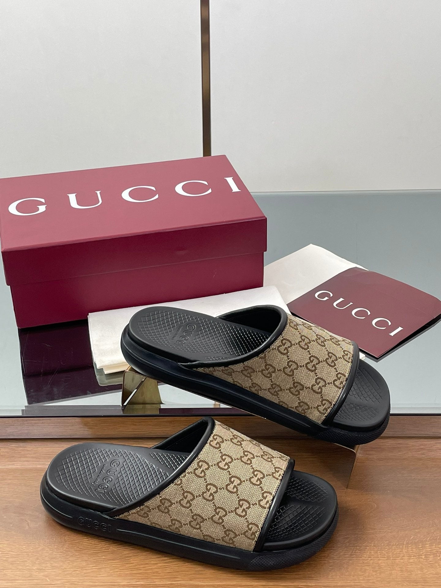 Gucci slide sandals with beige GG canvas straps and black rubber footbeds