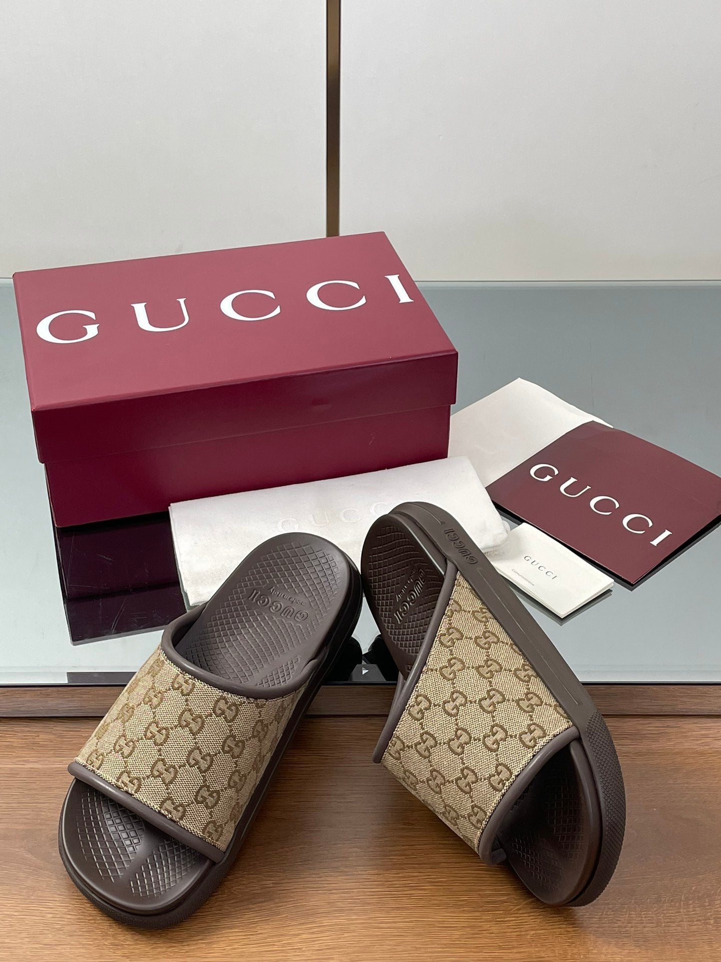 Gucci slide sandals with tan GG patterned straps and dark rubber footbeds